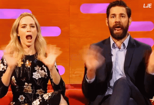 A Man And A Woman Are Sitting On A Couch With Their Hands In The Air And The Letters Lje Are On The Bottom GIF