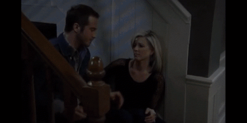 A Man And A Woman Are Sitting On A Set Of Stairs Talking To Each Other GIF