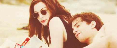 A Man And A Woman Are Sitting On The Beach . GIF