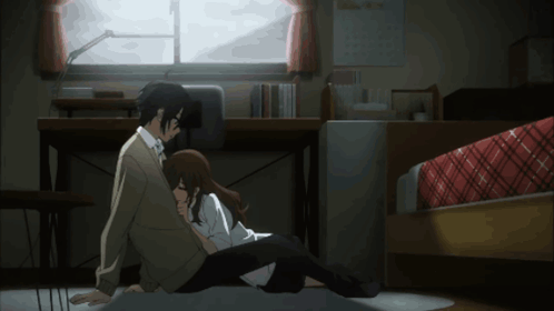 A Man And A Woman Are Sitting On The Floor Hugging Each Other GIF