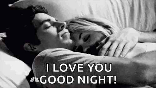 A Man And A Woman Are Sleeping In A Bed And The Man Is Hugging The Woman . GIF