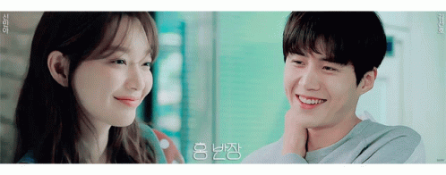 A Man And A Woman Are Smiling And Looking At Each Other In A Room . GIF