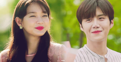 A Man And A Woman Are Smiling And Looking At The Camera GIF