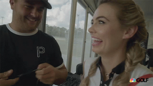 A Man And A Woman Are Smiling And The Woman Is Wearing A Shirt With The Letter P On It GIF