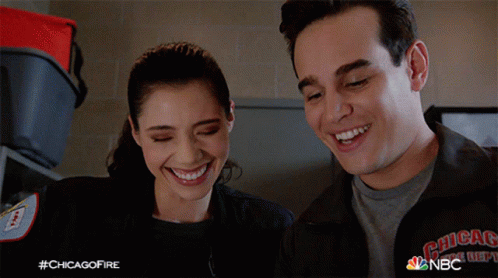 A Man And A Woman Are Smiling And Wearing A Jacket That Says Chicago Fire Department GIF