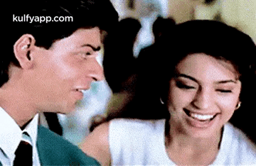 A Man And A Woman Are Smiling At Each Other . GIF