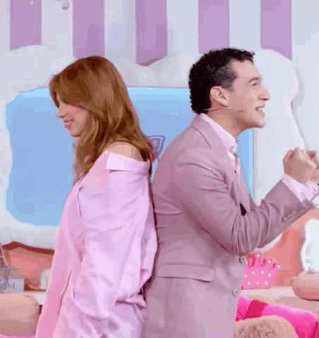 A Man And A Woman Are Standing Back To Back And The Woman Is Wearing A Pink Shirt . GIF