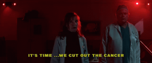 A Man And A Woman Are Standing In A Dark Room With The Words " It 'S Time We Cut Out The Cancer " Above Them GIF