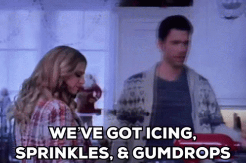 A Man And A Woman Are Standing In A Kitchen And The Woman Is Saying `` We 'Ve Got Icing , Sprinkles GIF