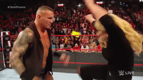 A Man And A Woman Are Standing In A Wrestling Ring . GIF