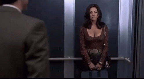A Man And A Woman Are Standing In An Elevator . GIF