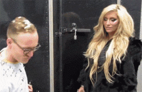 A Man And A Woman Are Standing In Front Of A Black Door GIF