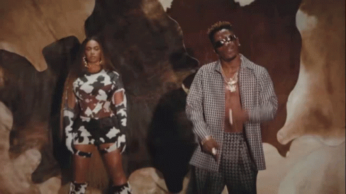 A Man And A Woman Are Standing In Front Of A Cow Skin GIF