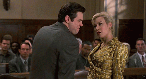 A Man And A Woman Are Standing In Front Of A Crowd In A Court Room GIF