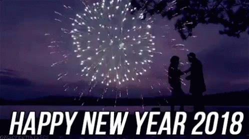 A Man And A Woman Are Standing In Front Of A Fireworks Display With The Words `` Happy New Year 2018 '' . GIF