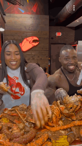 A Man And A Woman Are Standing In Front Of A Large Plate Of Food .. GIF