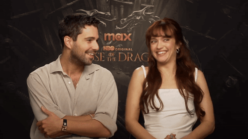 A Man And A Woman Are Standing In Front Of A Poster For Max Hbo Original GIF