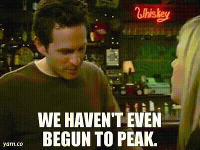 A Man And A Woman Are Standing In Front Of A Whiskey Sign And Talking To Each Other . GIF