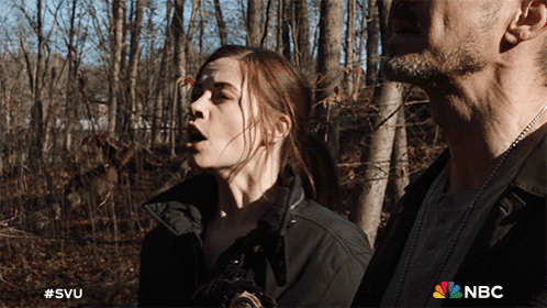 A Man And A Woman Are Standing In The Woods With A Nbc Logo On The Bottom GIF