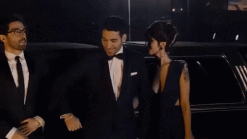 A Man And A Woman Are Standing Next To A Limousine . GIF