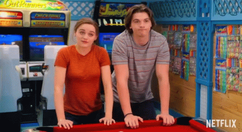 A Man And A Woman Are Standing Next To A Pool Table With Netflix Written On It GIF