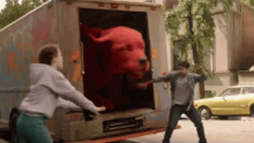 A Man And A Woman Are Standing Next To A Truck With A Stuffed Animal In The Back . GIF