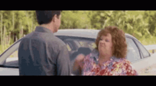 A Man And A Woman Are Standing Next To A White Car . GIF