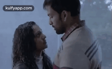 A Man And A Woman Are Standing Next To Each Other And Kissing In The Rain . GIF