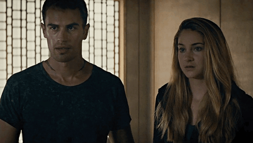 A Man And A Woman Are Standing Next To Each Other And Looking At The Camera GIF