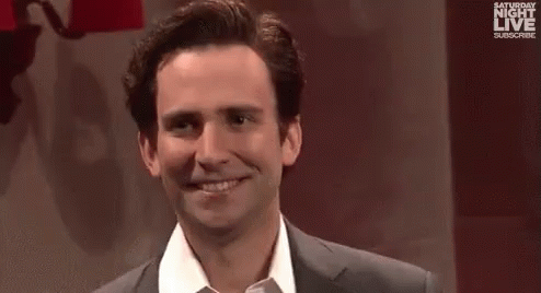 A Man And A Woman Are Standing Next To Each Other And Smiling At The Camera . GIF