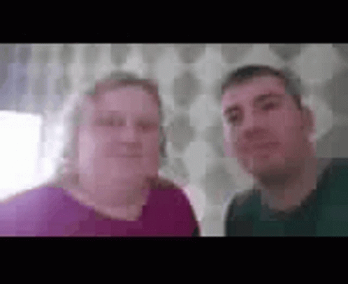 A Man And A Woman Are Standing Next To Each Other And Smiling For A Picture . GIF