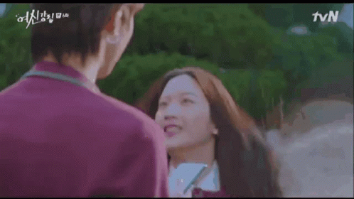 A Man And A Woman Are Standing Next To Each Other And Smiling . The Woman Is Wearing A School Uniform . GIF