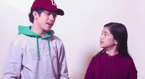A Man And A Woman Are Standing Next To Each Other And Talking To Each Other . GIF