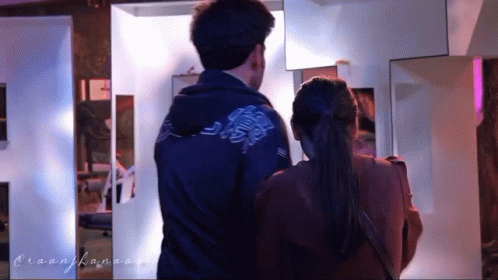 A Man And A Woman Are Standing Next To Each Other And The Man Is Wearing A Blue Jacket GIF