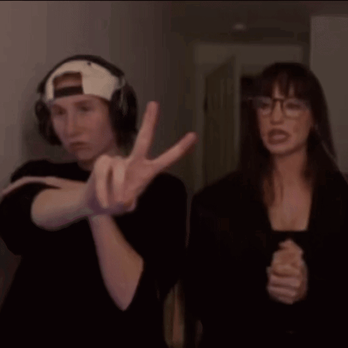 a man and a woman are standing next to each other and the man is wearing headphones and the woman is wearing glasses