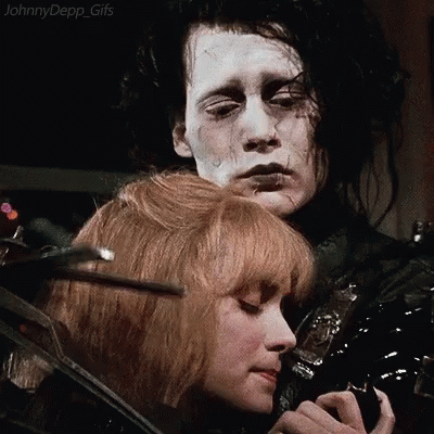 A Man And A Woman Are Standing Next To Each Other And The Woman Is Holding The Man 'S Hair . GIF