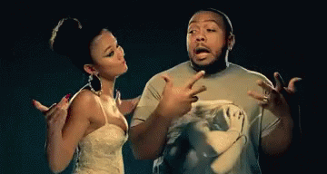 A Man And A Woman Are Standing Next To Each Other And The Woman Is Pointing At The Man GIF