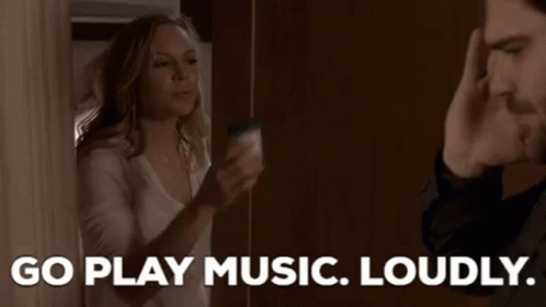 a man and a woman are standing next to each other and the woman is saying `` go play music loudly ''