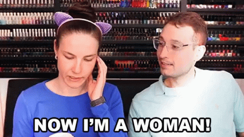 A Man And A Woman Are Standing Next To Each Other And The Woman Is Saying Now I 'M A Woman GIF