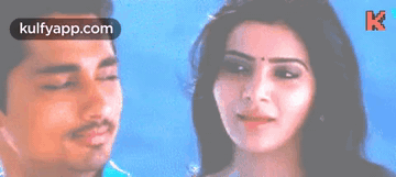 A Man And A Woman Are Standing Next To Each Other And The Woman Is Smiling . GIF