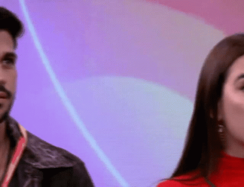 a man and a woman are standing next to each other and the woman is wearing a red turtleneck