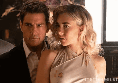 A Man And A Woman Are Standing Next To Each Other And The Woman Is Wearing A White Dress And The Man Is Wearing A Suit GIF