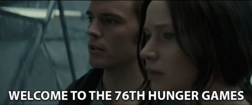 A Man And A Woman Are Standing Next To Each Other And The Words Welcome To The 76Th Hunger Games Are On The Screen GIF