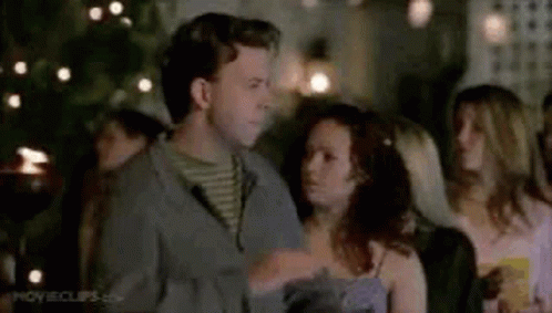 A Man And A Woman Are Standing Next To Each Other At A Party . GIF
