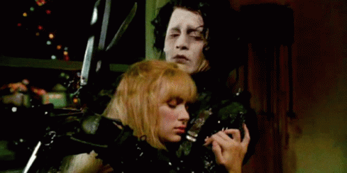 A Man And A Woman Are Standing Next To Each Other Holding A Pair Of Scissors . GIF