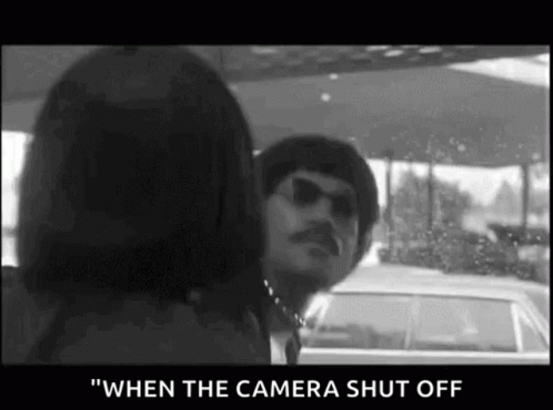 A Man And A Woman Are Standing Next To Each Other In A Car And The Camera Is Shut Off . GIF