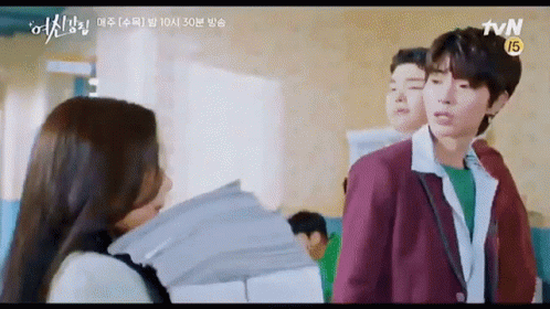 A Man And A Woman Are Standing Next To Each Other In A Classroom . GIF