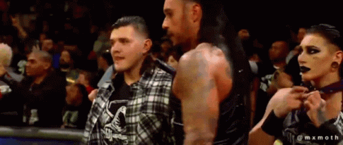 A Man And A Woman Are Standing Next To Each Other In A Crowd GIF
