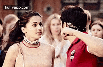 A Man And A Woman Are Standing Next To Each Other In A Crowd Of People . GIF