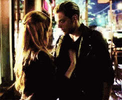 A Man And A Woman Are Standing Next To Each Other In A Dark Room GIF